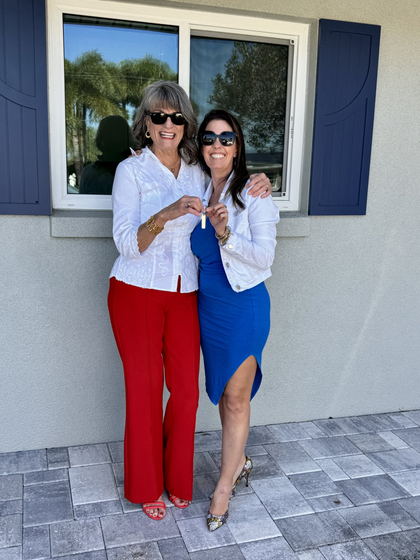 Julie and Eileen Bedinghaus outside the front door, key held up, both laughing.
