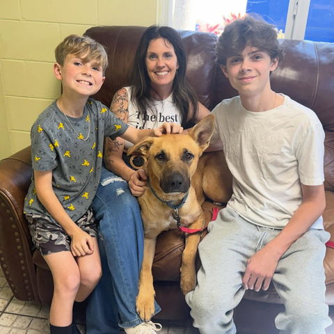 Jules on a couch with her two sons and Charlie, the dog they adopted that day, in the shelter&rsquo;s meeting room.