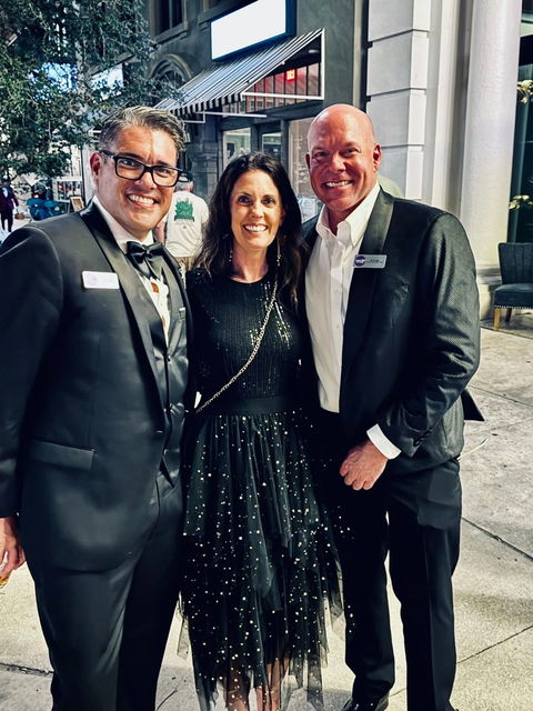 Jules with Gabe Alves and Rob Hall on the sidewalk at the Winter Pride Ball in St. Petersburg, all in formalwear.